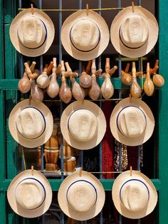 many hats are hanging on a rack in front of a green door with blue trim