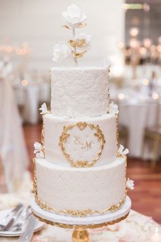 a white and gold wedding cake sitting on top of a table