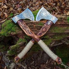 two axes are sitting next to each other on some moss covered ground with leaves around them