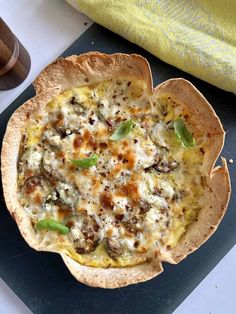 a pizza sitting on top of a pan covered in cheese and toppings next to a cup