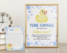 a wooden frame with a rubber ducky on it next to a notepad and clock