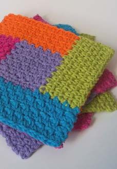 four crocheted dishcloths stacked on top of each other in different colors