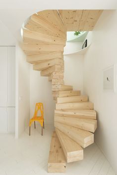 an orange chair sitting on top of a wooden staircase next to a white wall and stairs