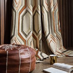 an open book sitting on top of a wooden floor next to a leather poufce