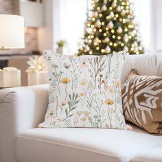 a living room with a christmas tree in the background and pillows on the couches