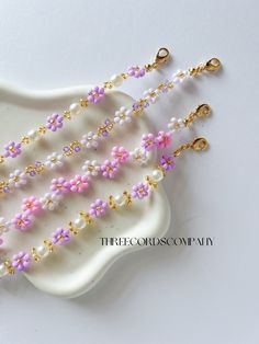 three strands of pink and white beads with gold clasps on a white platter