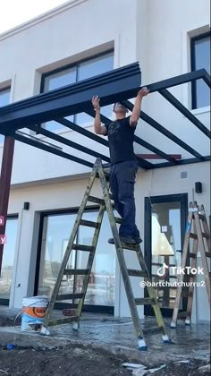 a man standing on top of a ladder next to a building