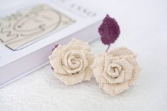 two small crocheted flowers sitting on top of a table next to a book