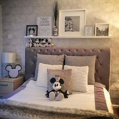 a bed with mickey mouse stuffed animal on it's head and pillows in the middle