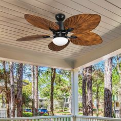 a ceiling fan sitting on top of a wooden porch next to a white picket fence