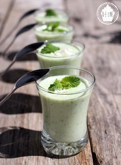 three glasses filled with green smoothie and garnished with mint on wooden table