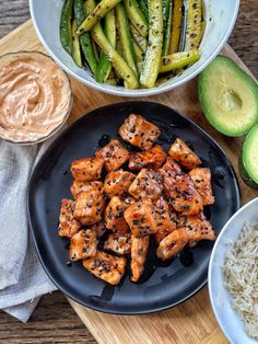 the meal is ready to be eaten on the wooden cutting board with avocado and rice