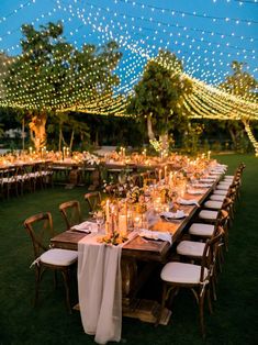 an outdoor dinner setup with white linens and string lights strung over the tables at night