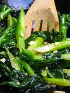 a wooden spoon is being used to stir broccoli and other vegetables in a wok