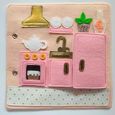 a pink felt applique with an oven, sink and teapot on it