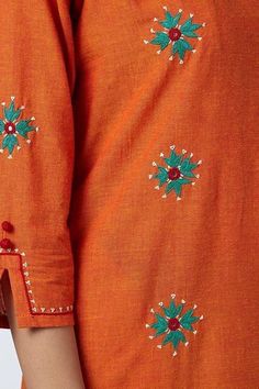 an orange shirt with green and red flowers on it's chest, showing the back