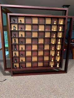 an old wooden chess board with many pieces on display in front of a glass door