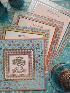 three cards with designs on them sitting next to a vase and some other items in front of it