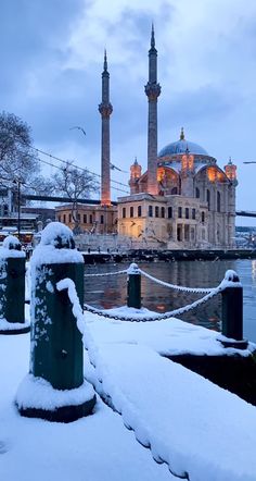 the blue mosque is surrounded by snow on the ground and in front of some water