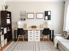 a living room with two chairs and a desk in the corner, along with pictures on the wall