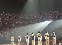 a group of men standing on top of a stage in front of a large crowd