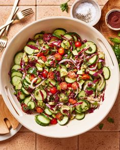 a white bowl filled with cucumber and red onion salad next to silverware