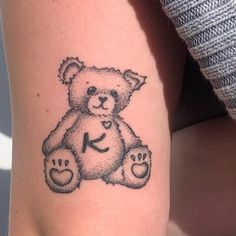 a small teddy bear tattoo on the arm