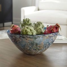 a bowl filled with flowers sitting on top of a wooden table