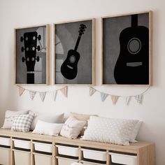 three framed guitars hang on the wall above a bench with pillows and baskets underneath them