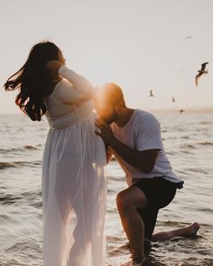 a man kneeling down next to a woman in the water