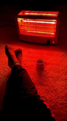 a person laying on the floor in front of an air conditioner and coffee cup