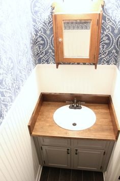 a bathroom with a sink, mirror and blue wallpaper on the walls in it