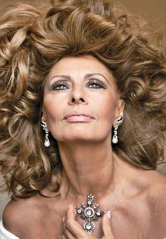 a woman with her hair blowing in the wind, wearing earrings and a white dress