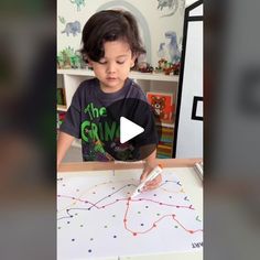 a little boy that is standing in front of a table with some markers on it