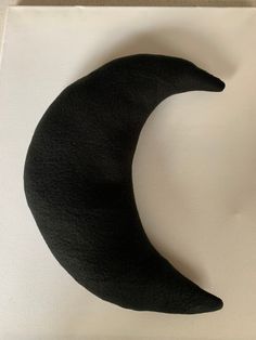 a black crescent shaped object sitting on top of a white surface with a shadow over it