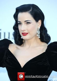 a woman in black dress with red lipstick and pearls on her head, posing for the camera