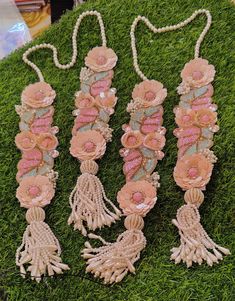 three tassels with flowers on them are laying in the grass and one has beads