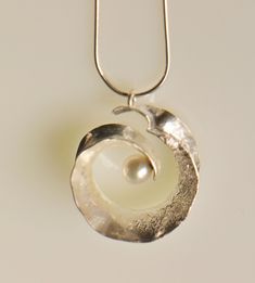 "This pendant is forged from one sheet of sterling silver. I hammer the silver into shape using the technique of anticlastic forming. I add texture to one side of the pendant through reticulation, and set a 7mm white freshwater pearl in the middle. The pendant measures a bit over 1\" in diameter, and has a depth of 1/2\". It comes on a 16\" or 18\" sterling silver snake chain - for a different chain length, please convo me." Elegant Hand Cast Necklaces For Anniversary, Elegant Hand Cast Necklace For Anniversary, Metal Pendant Necklace, Spiral Pendant, Soldering Jewelry, Modernist Jewelry, Pewter Pendant, Silver Jewelry Design, Durham Nc