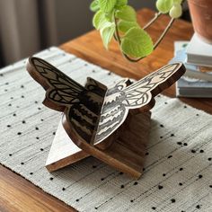 a wooden sculpture sitting on top of a table next to a potted plant