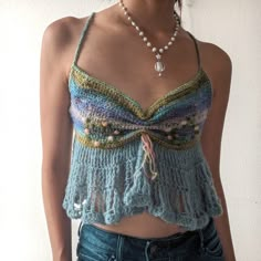 a woman wearing a crochet top and pearls