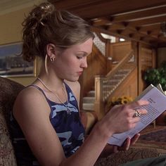 a woman sitting in a chair reading a book