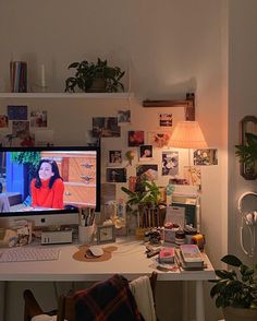 a desk with a computer, lamp and pictures on the wall