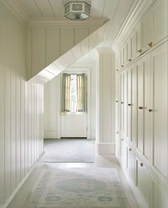 an empty hallway with white walls and cabinets