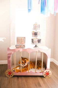 a tiger laying inside of a pink toy car on top of a hard wood floor