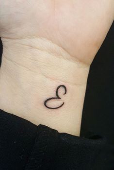 a woman's wrist tattoo with the letter q on it