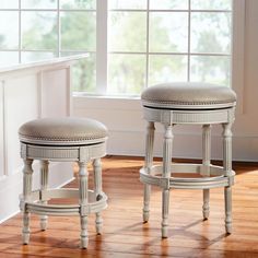 two white stools sitting on top of a hard wood floor next to a window