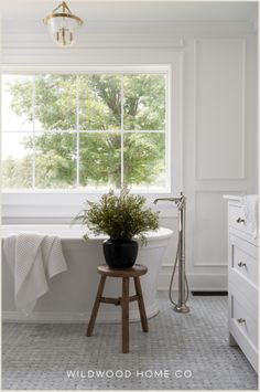 a white bathroom with a tub and window