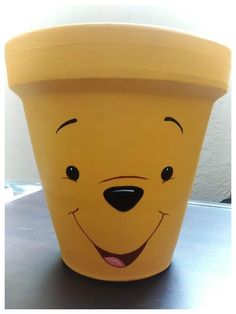 a winnie the pooh plastic cup sitting on top of a table next to a wall