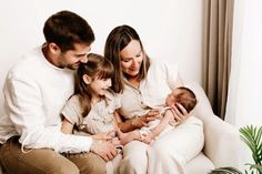 a family sitting on a couch holding their babies