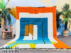 a colorful rug on the floor in front of a chair and potted palm trees